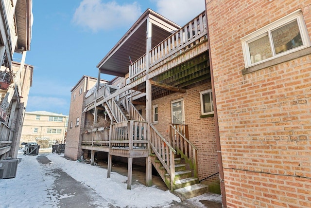 8307 N Christiana Ave Unit 2W, Skokie, IL 60076 - snow covered house featuring stairs, brick siding, cooling unit, and a deck