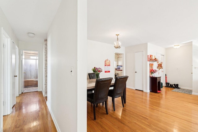 dining area featuring a chandelier, wood finished floors, and baseboards