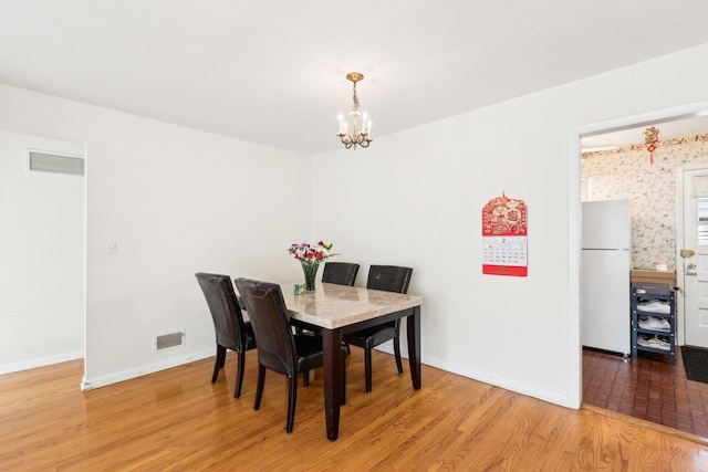 dining room with baseboards, visible vents, an inviting chandelier, and wood finished floors