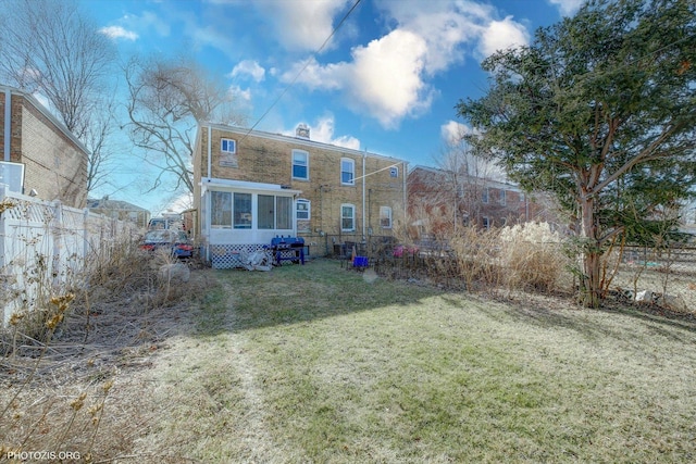 back of house with a yard, fence, and a sunroom