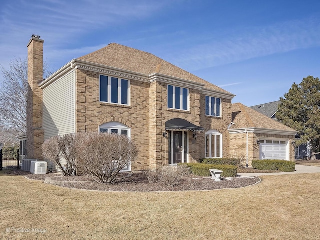 colonial-style house featuring a garage, a front yard, and central air condition unit