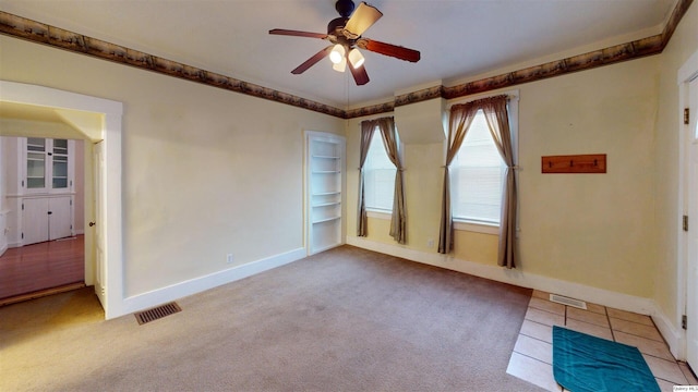 empty room featuring light carpet, crown molding, and ceiling fan