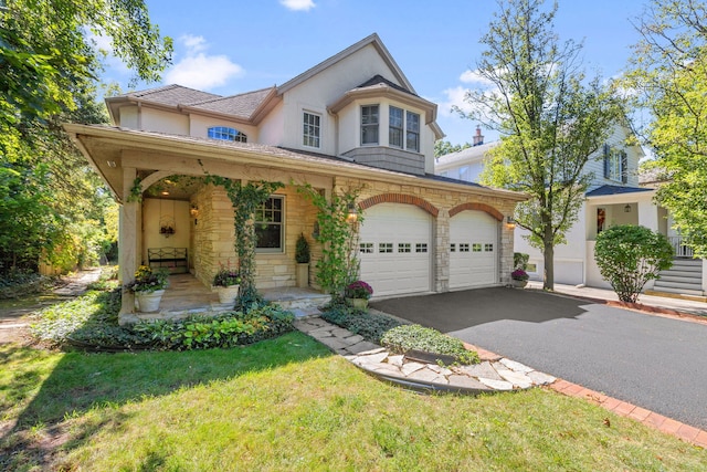 view of front of house with a garage, a front yard, and covered porch