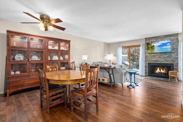 dining area with ceiling fan, a fireplace, and dark hardwood / wood-style flooring