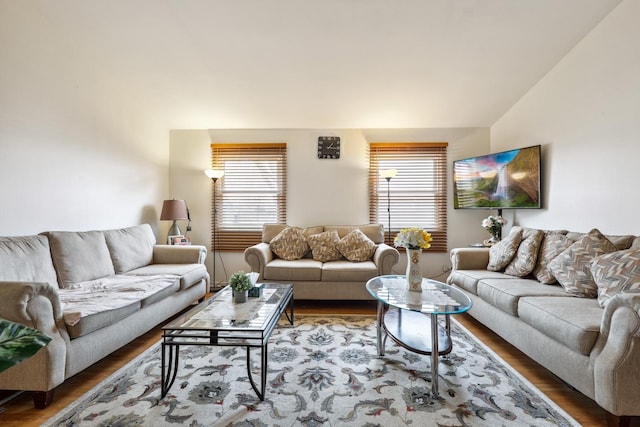 living area with lofted ceiling, a wealth of natural light, and wood finished floors