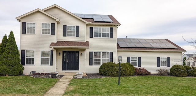 view of front of property featuring a front yard and solar panels