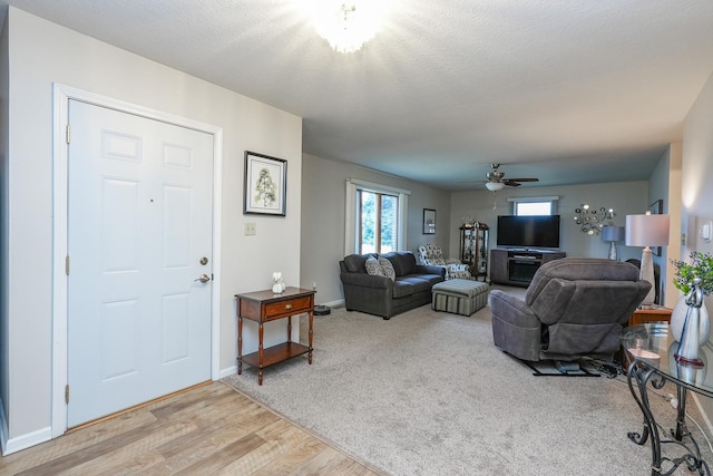 living room with a textured ceiling, light hardwood / wood-style floors, and ceiling fan