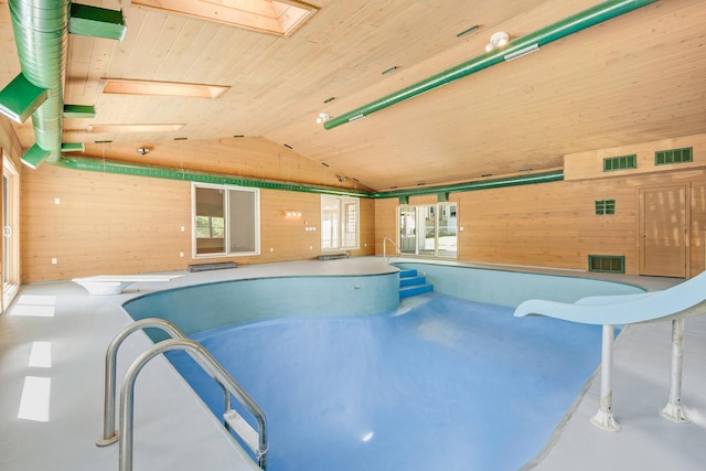 view of swimming pool featuring a skylight, a hot tub, a diving board, and a water slide