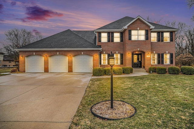 view of front of home featuring driveway, a garage, a lawn, and brick siding