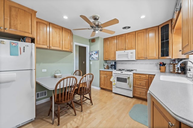 kitchen featuring visible vents, white appliances, light wood-style floors, and a sink