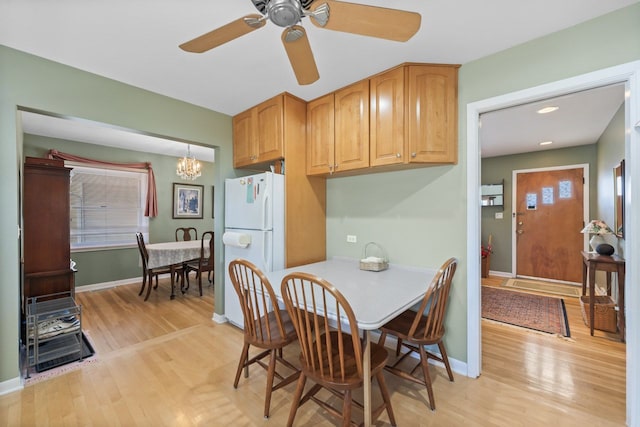 dining area featuring baseboards, light wood-style floors, and ceiling fan with notable chandelier