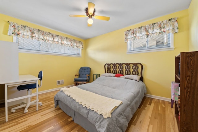 bedroom with ceiling fan, wood finished floors, visible vents, and baseboards