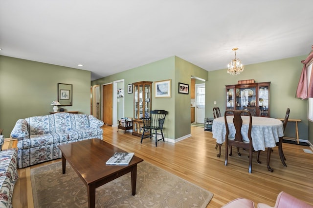 living room with baseboards, light wood-type flooring, and a chandelier