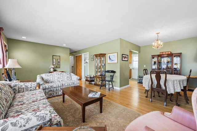 living room featuring recessed lighting, baseboards, light wood finished floors, and a chandelier