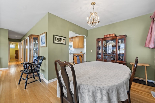 dining room featuring baseboards, a chandelier, and light wood finished floors