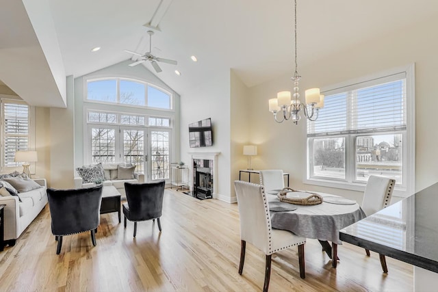 dining space with high vaulted ceiling, a notable chandelier, plenty of natural light, and light hardwood / wood-style floors