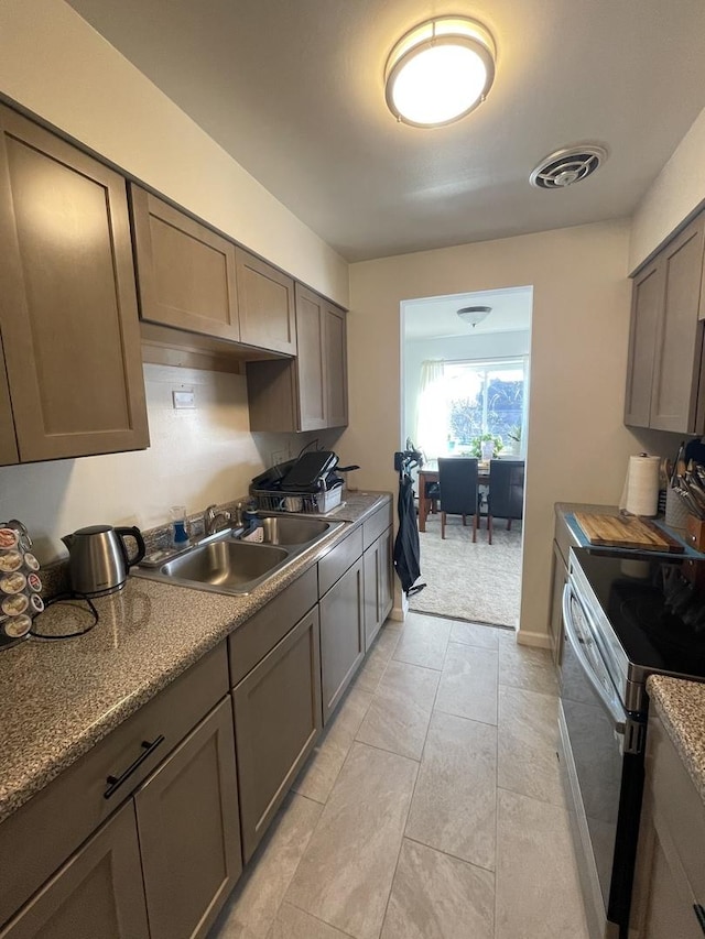 kitchen featuring sink, light tile patterned floors, and stainless steel range with electric stovetop