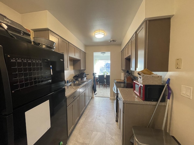 kitchen featuring black fridge, sink, and stainless steel range with electric cooktop