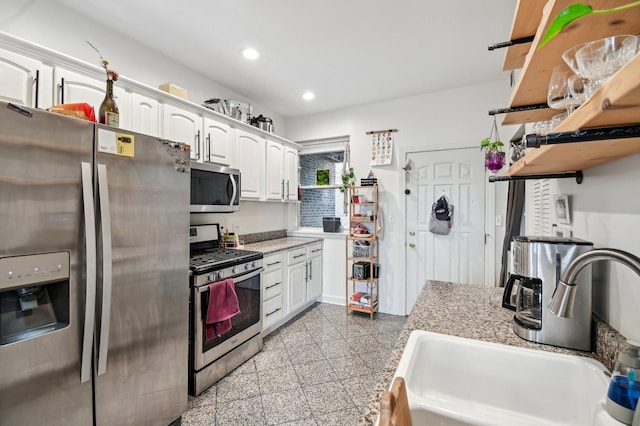 kitchen with recessed lighting, granite finish floor, a sink, white cabinetry, and appliances with stainless steel finishes