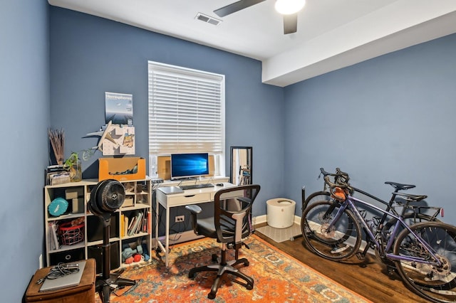 office space with baseboards, wood finished floors, visible vents, and a ceiling fan