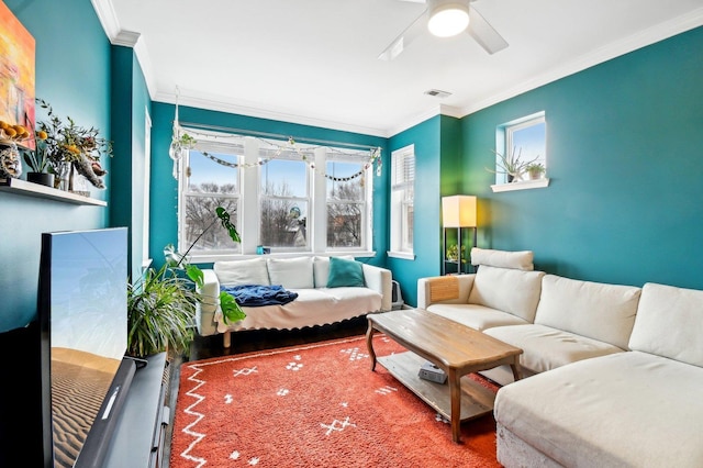 living area with ornamental molding, visible vents, and ceiling fan