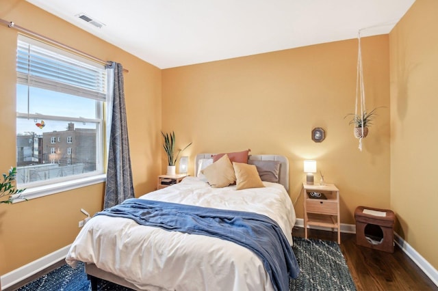 bedroom with wood finished floors, visible vents, and baseboards