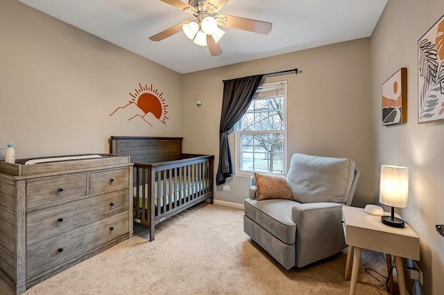 carpeted bedroom featuring a nursery area and ceiling fan