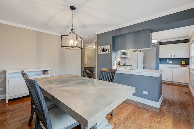 dining area featuring crown molding, sink, and light wood-type flooring