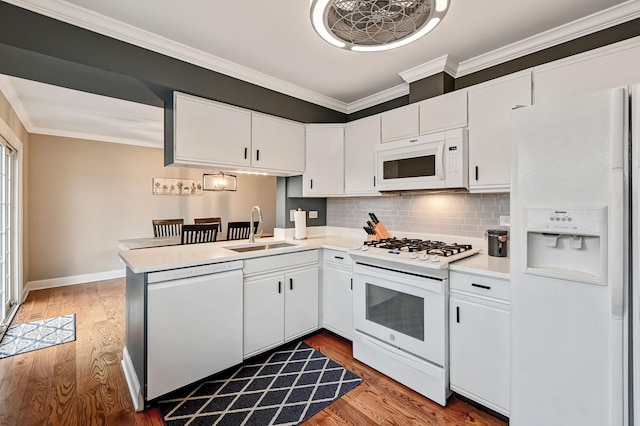 kitchen featuring sink, white appliances, white cabinetry, ornamental molding, and kitchen peninsula