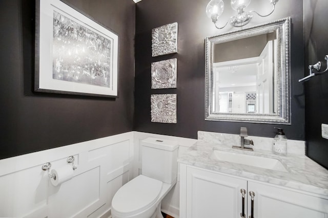 bathroom featuring vanity, a notable chandelier, and toilet