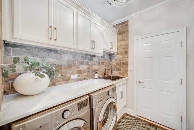 washroom with cabinets, ornamental molding, sink, and washing machine and clothes dryer