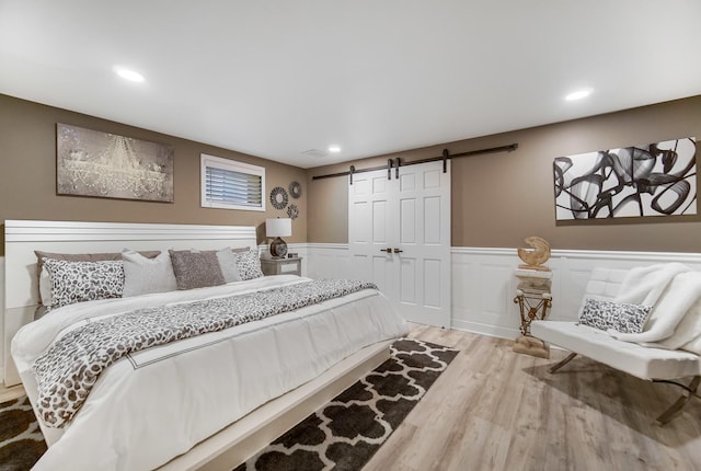 bedroom featuring hardwood / wood-style flooring and a barn door