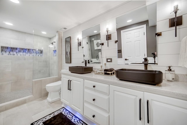 bathroom featuring a tile shower, vanity, tile patterned floors, and toilet