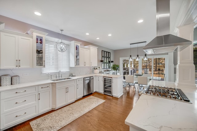 kitchen featuring white cabinetry, island exhaust hood, stainless steel dishwasher, and decorative light fixtures