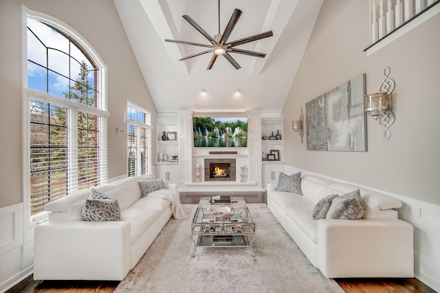 living room featuring high vaulted ceiling, built in features, hardwood / wood-style floors, and ceiling fan