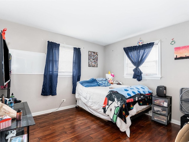 bedroom with multiple windows, wood-type flooring, and baseboards