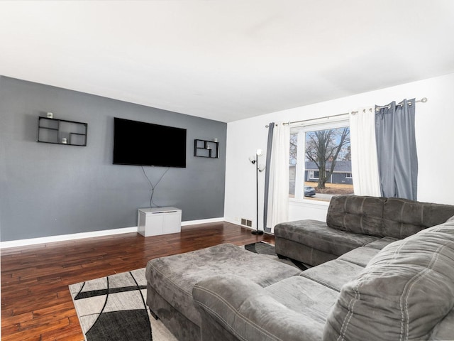 living area with wood finished floors, visible vents, and baseboards