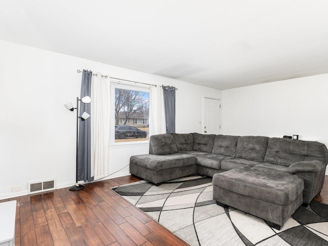 living room featuring visible vents, baseboards, and wood finished floors