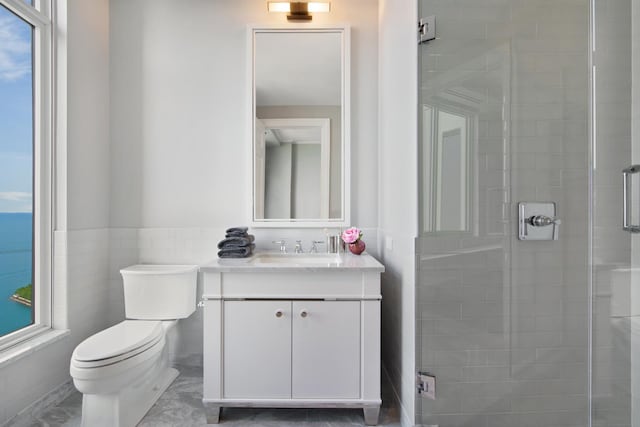 bathroom featuring vanity, a shower with door, toilet, and tile walls