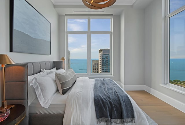 bedroom featuring wood-type flooring and a water view