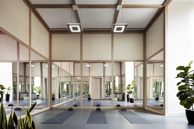 gym featuring a towering ceiling and floor to ceiling windows