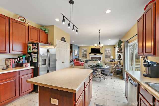 kitchen with a chandelier, light tile patterned floors, appliances with stainless steel finishes, a kitchen island, and pendant lighting