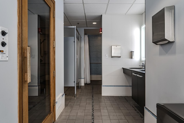 bathroom with tile patterned flooring, sink, a paneled ceiling, and walk in shower