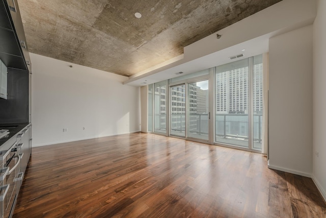 unfurnished living room featuring dark wood-type flooring and a wall of windows