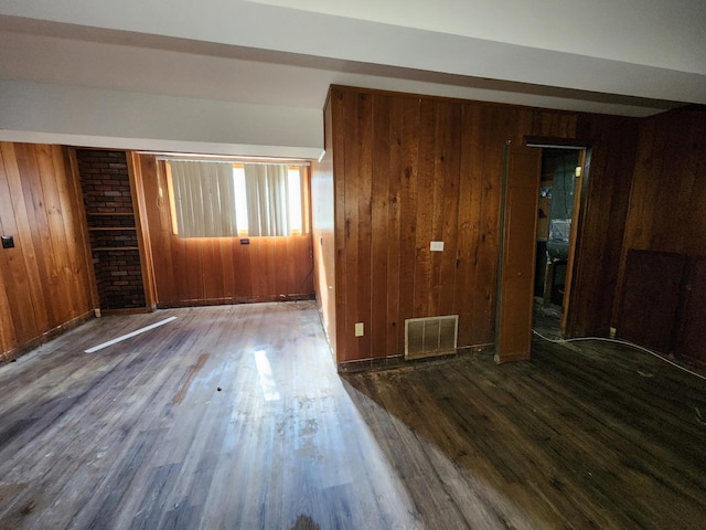 unfurnished room featuring hardwood / wood-style floors and wooden walls