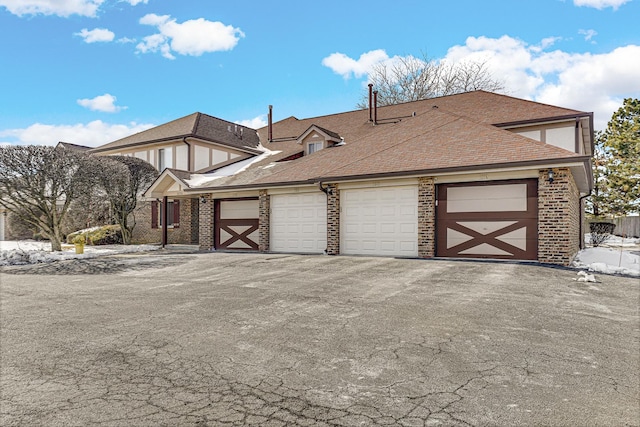 view of side of property featuring an attached garage, roof with shingles, and brick siding