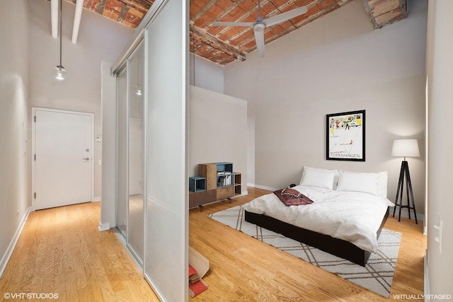 bedroom featuring a high ceiling, brick ceiling, and light hardwood / wood-style floors