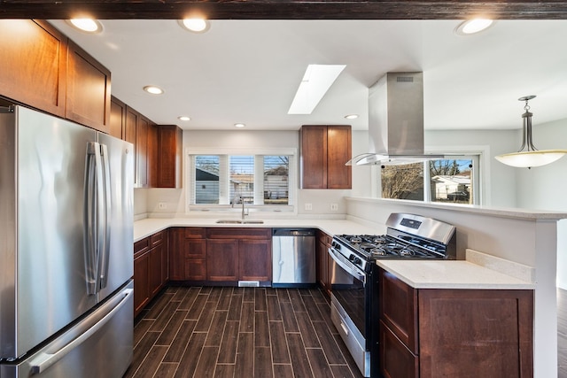 kitchen featuring pendant lighting, sink, a skylight, stainless steel appliances, and island range hood