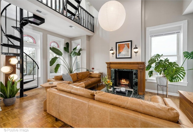 living area with visible vents, plenty of natural light, a high ceiling, and a premium fireplace