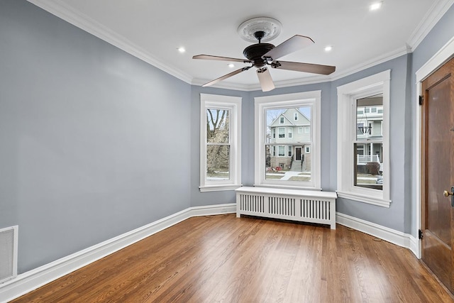 empty room featuring radiator, crown molding, wood-type flooring, and ceiling fan